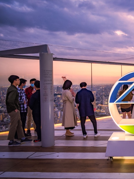 Tourists enjoying sunset views from Shibuya Sky Deck in Tokyo.