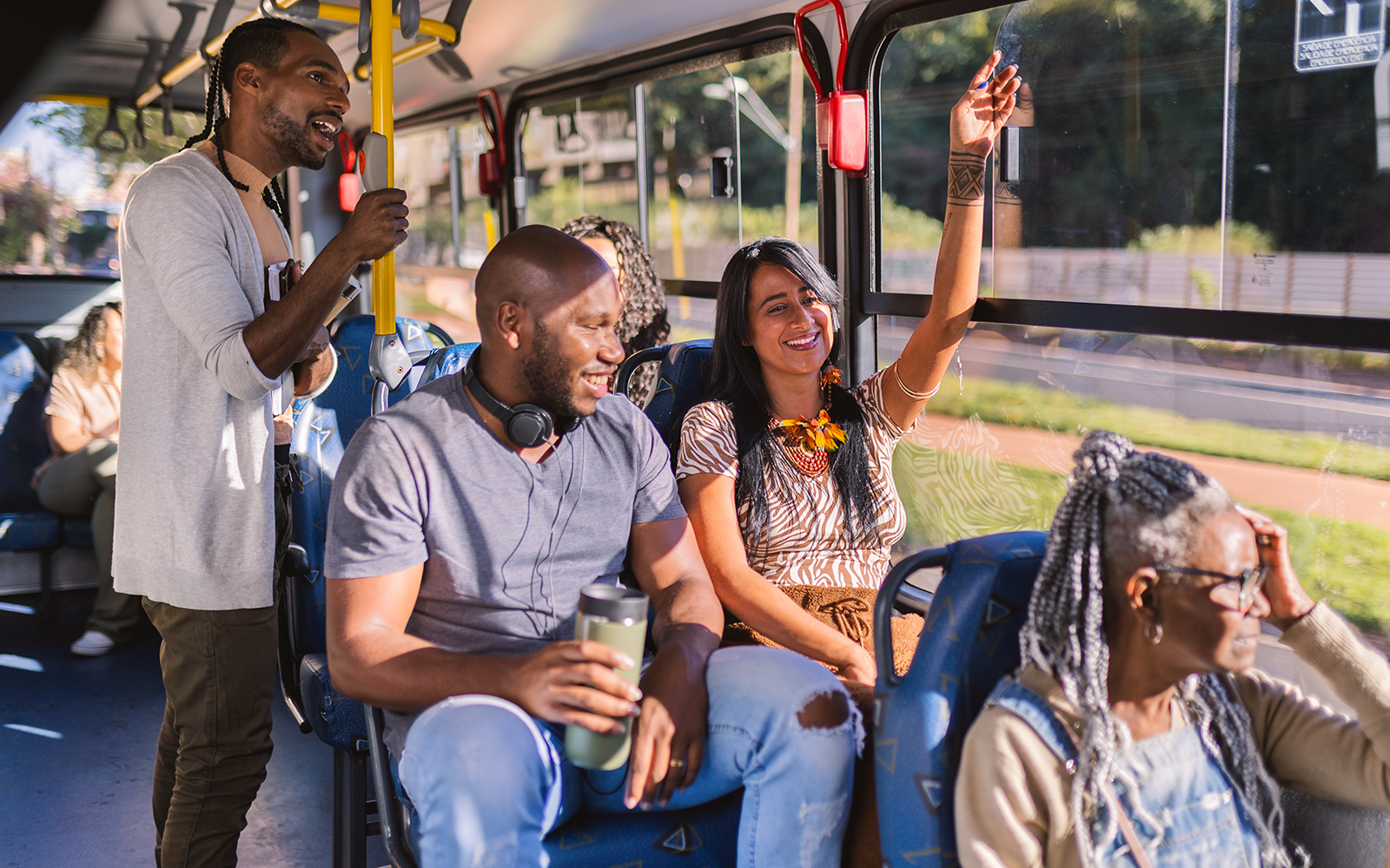 People talking inside a bus with yellow poles and blue seats