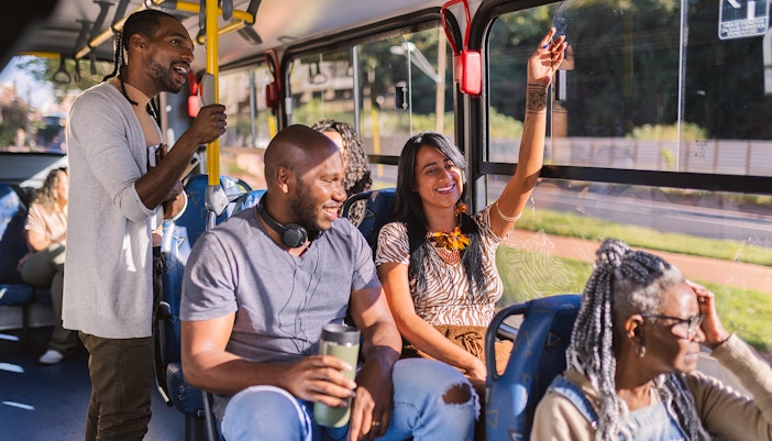 People talking inside a bus with yellow poles and blue seats