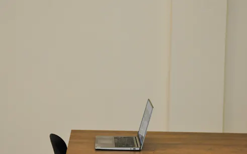 Laptop on a wooden table in an art space, Athens retreat.
