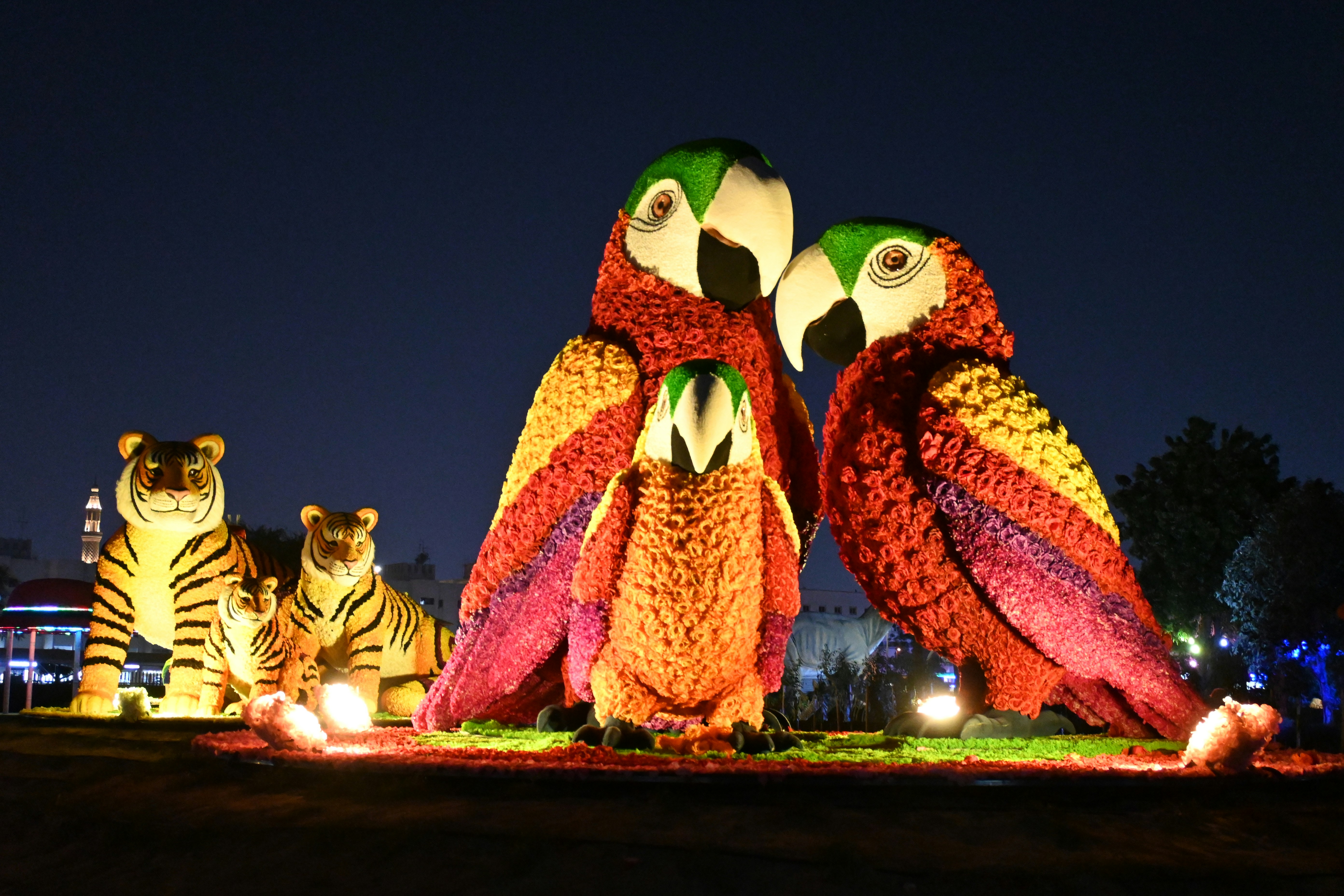 Floral parrot and tiger sculptures illuminated at night in Dubai Garden Glow.