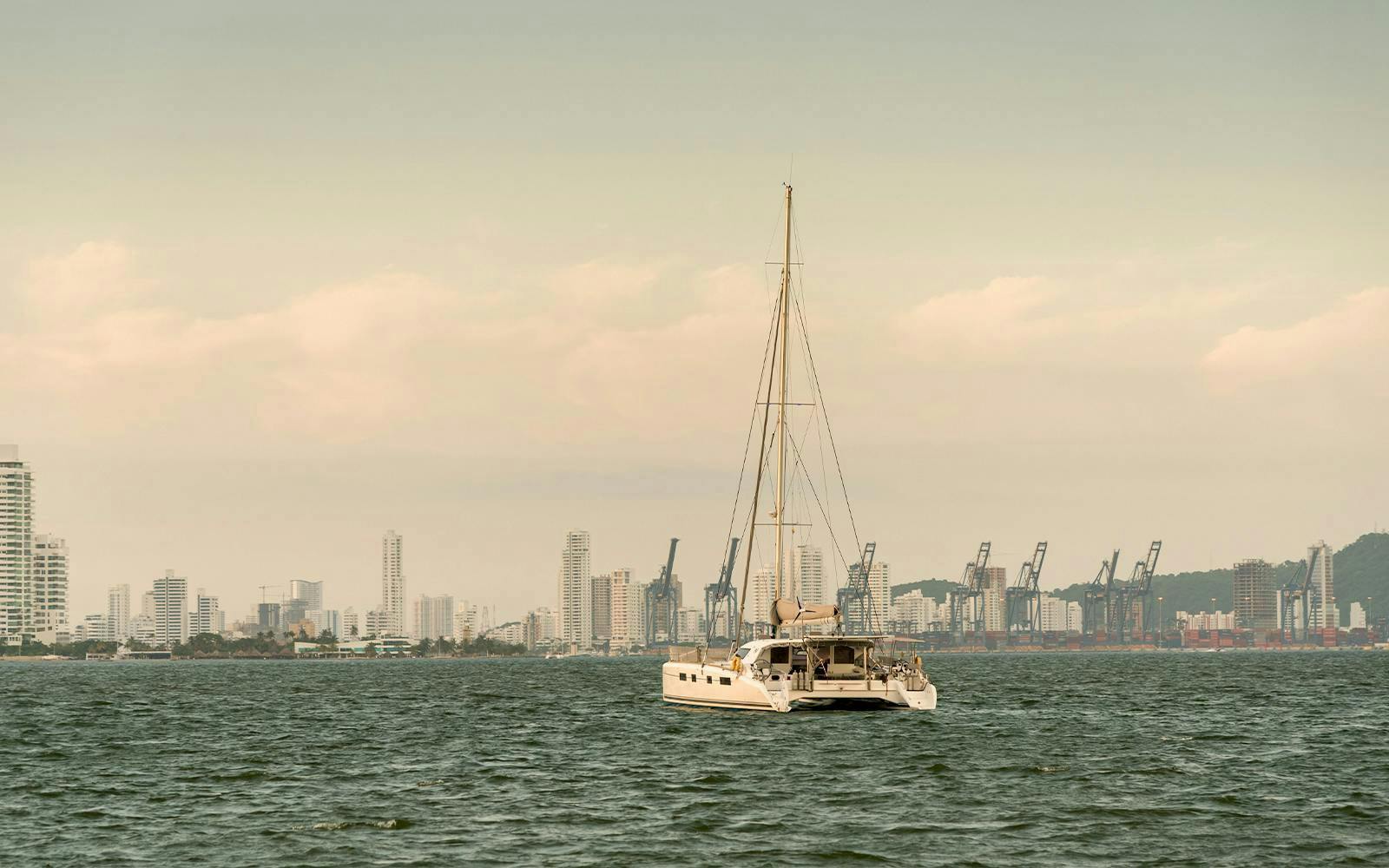 Sailboat on Cartagena Bay with city skyline in the background.