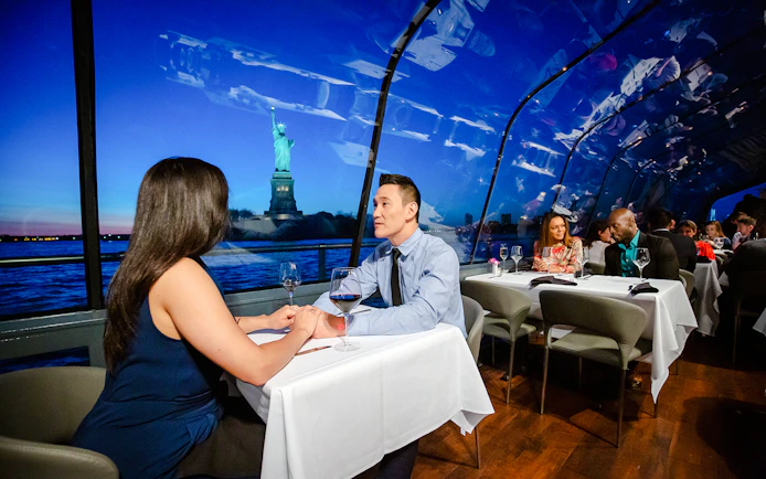 Couple dining on New Jersey Signature Cruise with Statue of Liberty view.