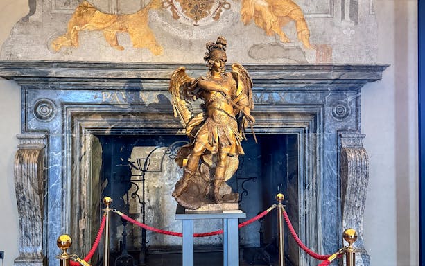 Statue of an angel inside Castel Sant'Angelo, Rome, with ornate backdrop.