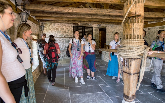 Tour group exploring a historic monastery interior in Meteora, Greece.