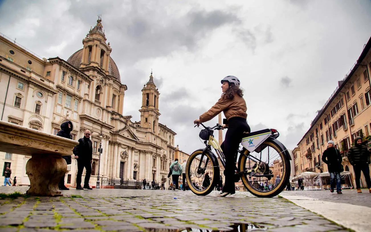 Cyclist on a bike tour at Piazza Navona with Sant'Agnese in Agone, Rome.