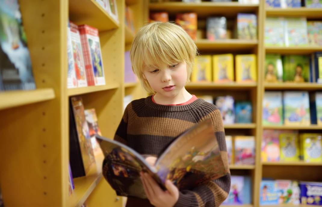 Child reading a comic book in a bookstore at the Comic Museum, Malta.