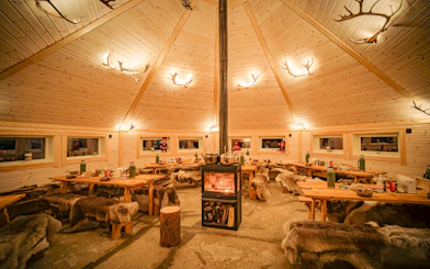 Cozy Sami tent interior with reindeer hides and central fireplace in Tromso.
