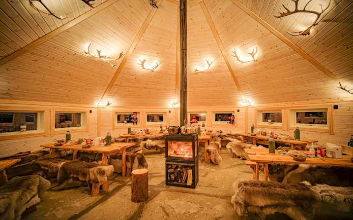 Cozy Sami tent interior with reindeer hides and central fireplace in Tromso.