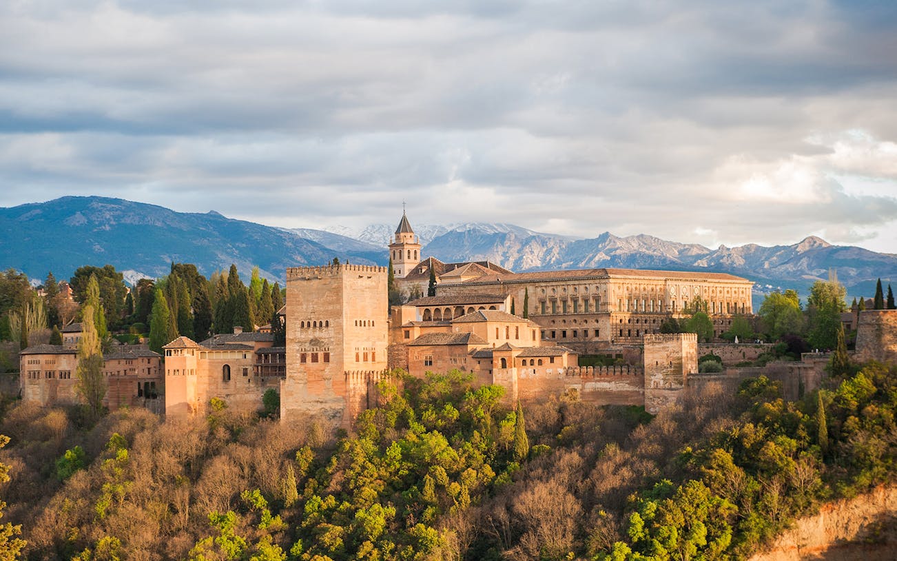 Alhambra Palace in Granada with surrounding landscape and mountains in the background.
