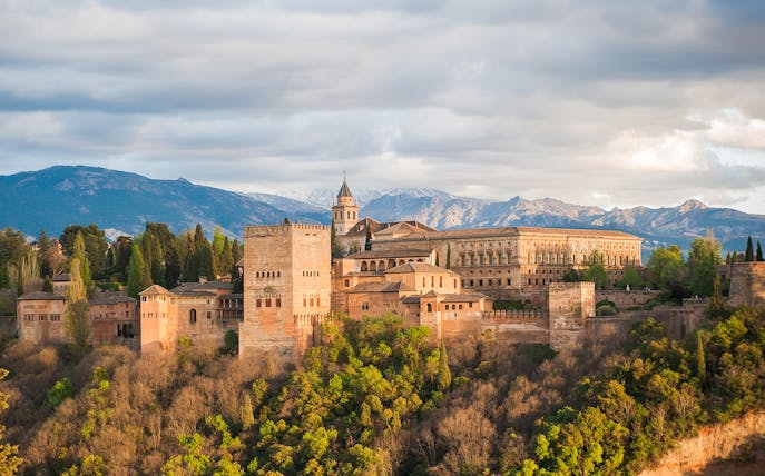 Alhambra Palace in Granada with surrounding landscape and mountains in the background.