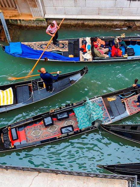 Gondolas navigating a busy canal in Venice, Italy.