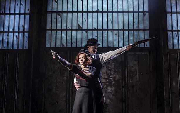 Bonnie and Clyde actors posing with guns in a dramatic stage setting.