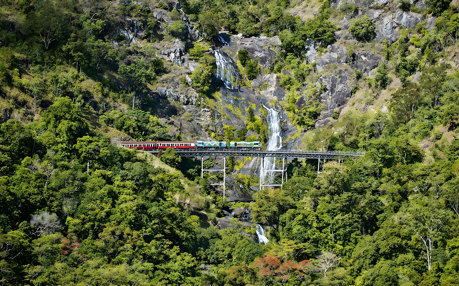 Kuranda Scenic Railway crossing Stoney Creek Falls in lush rainforest.