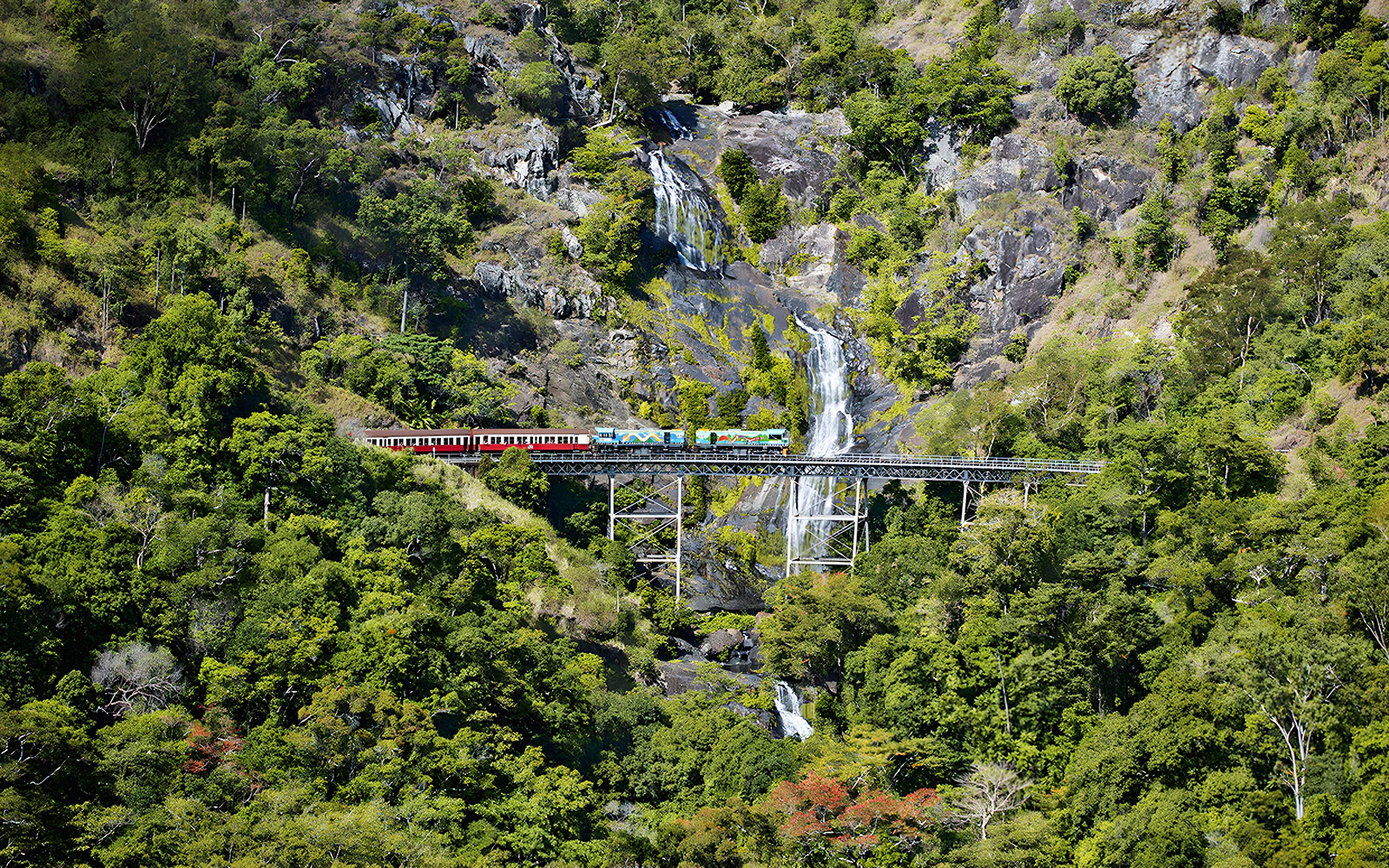 Kuranda Scenic Railway crossing Stoney Creek Falls in lush rainforest.