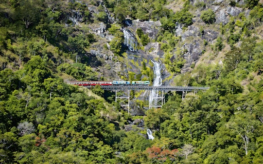 Kuranda Scenic Railway crossing Stoney Creek Falls in lush rainforest.