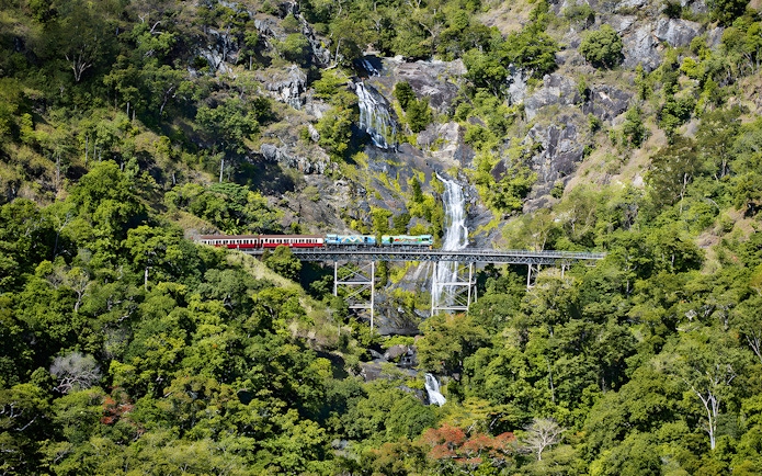 Kuranda Scenic Railway crossing Stoney Creek Falls in lush rainforest.