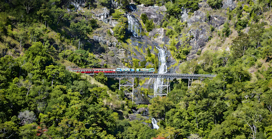 Kuranda Scenic Railway crossing Stoney Creek Falls in lush rainforest.