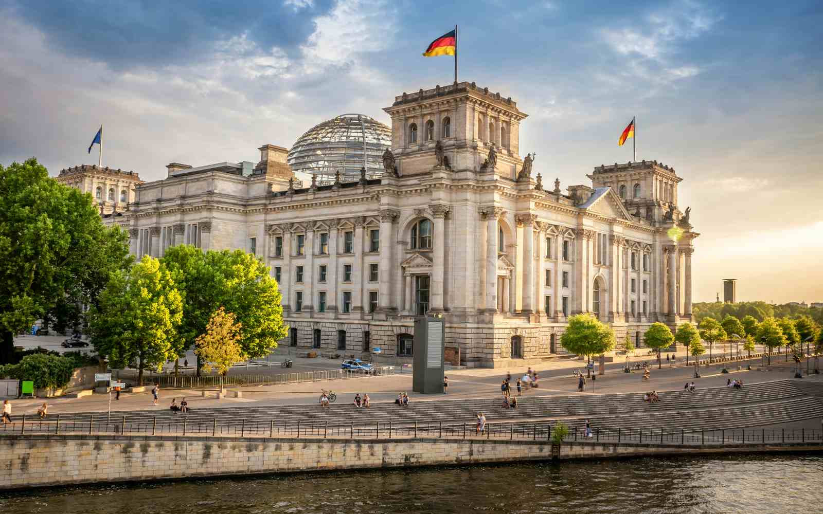 Reichstag building in Berlin's government district with glass dome and tourists.