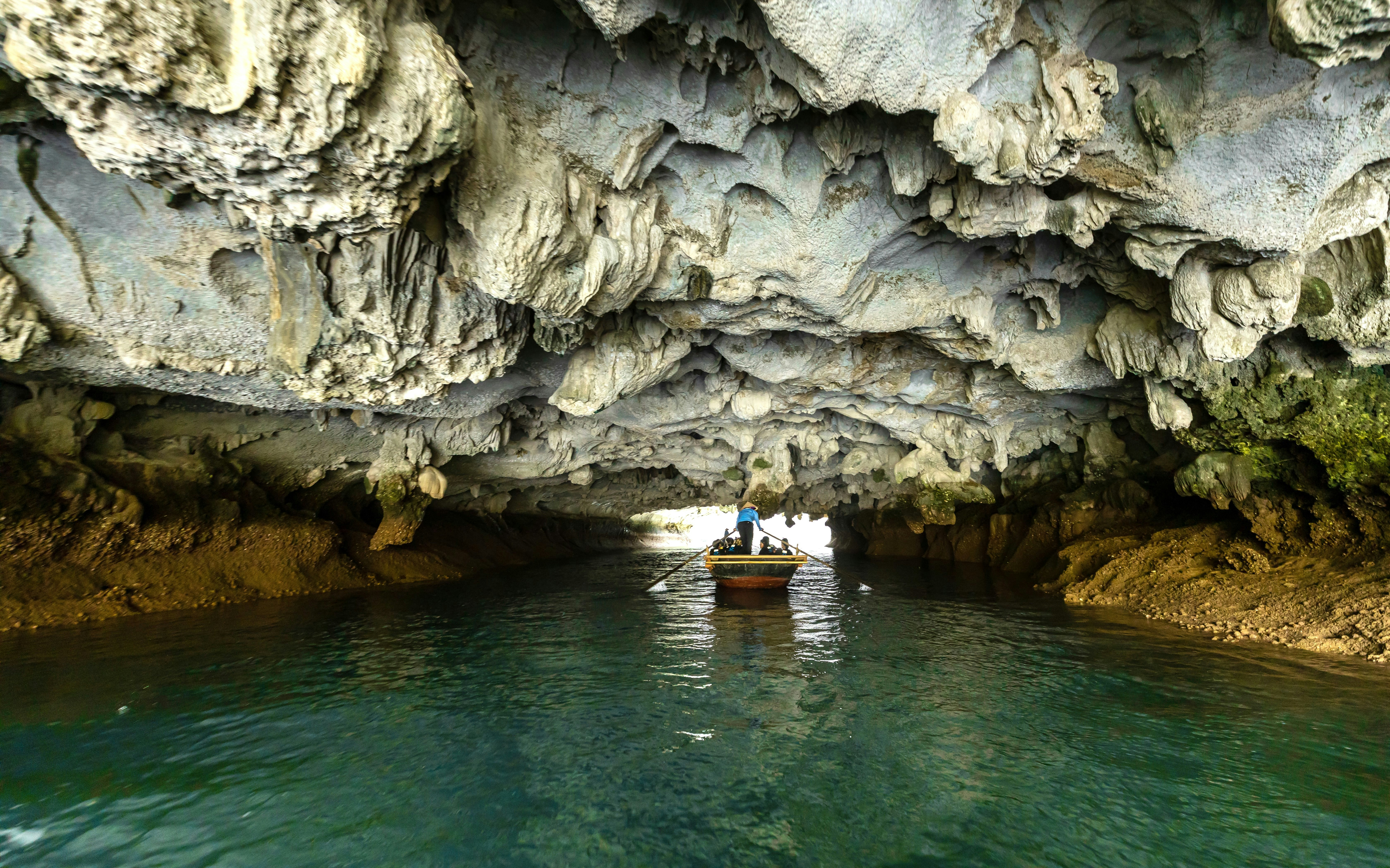 Boat navigating through limestone formations in Luon Cave, Halong Bay, Vietnam.