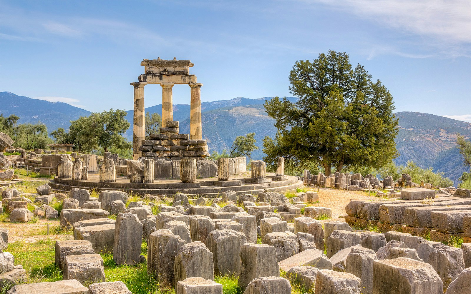 Temple of Apollo ruins at Delphi with mountainous backdrop.