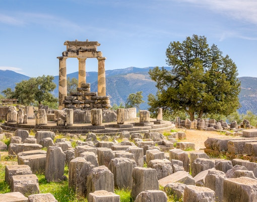 Temple of Apollo ruins at Delphi with mountainous backdrop.