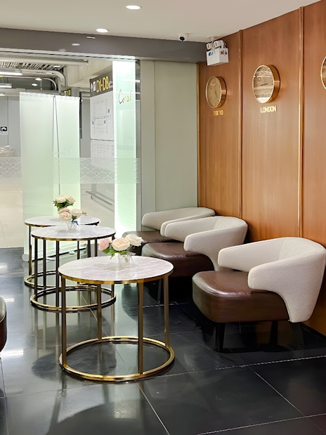 Seating area in Coral Finest Business Class Lounge, Bangkok airport, with clocks showing global times.