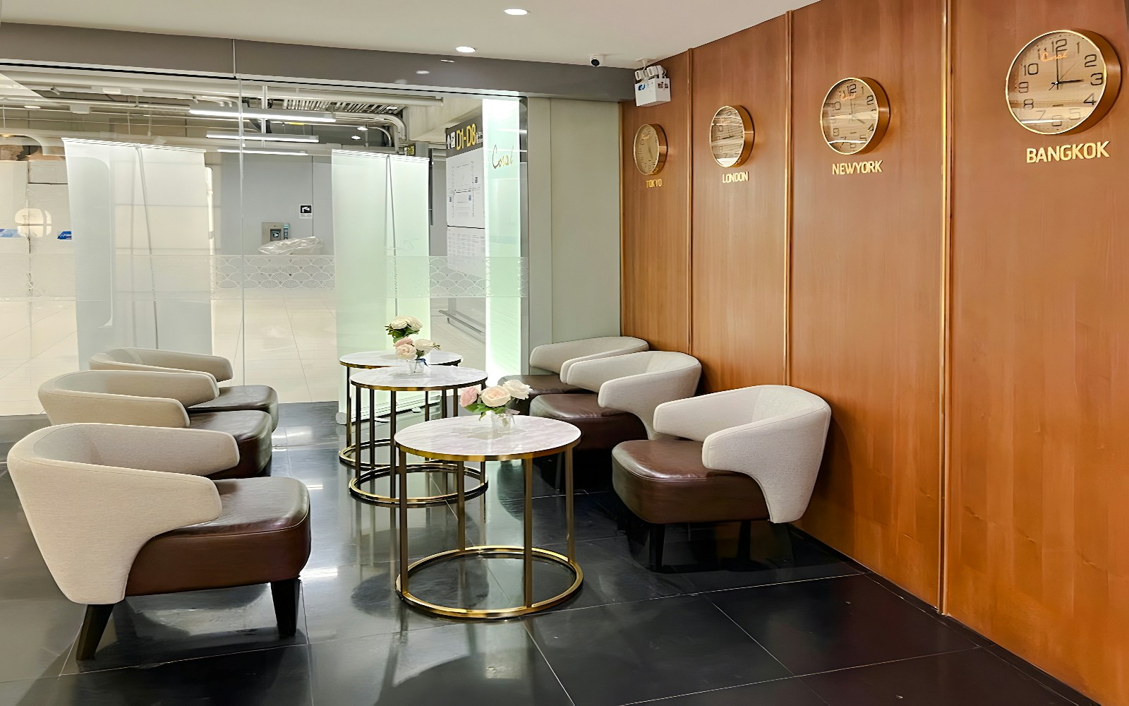 Seating area in Coral Finest Business Class Lounge, Bangkok airport, with clocks showing global times.