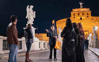 Tour group with guide on a haunted ghost tour near Castel Sant'Angelo, Rome at night.