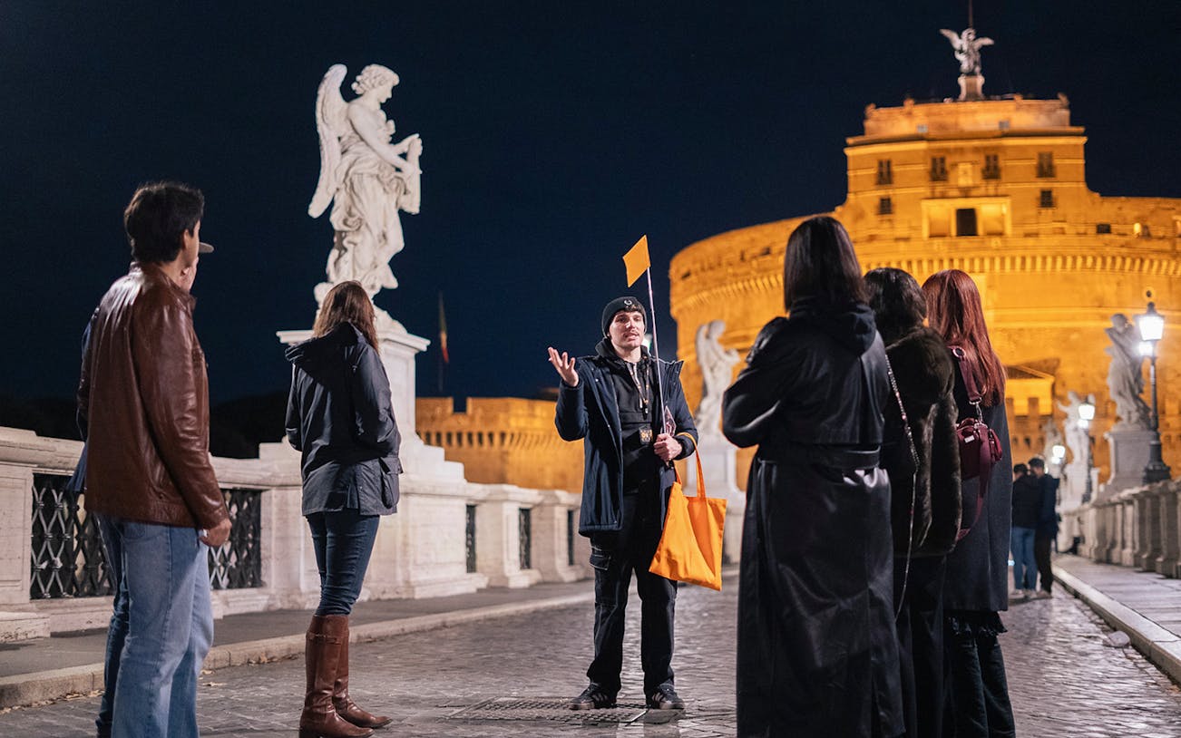 Tour group with guide on a haunted ghost tour near Castel Sant'Angelo, Rome at night.