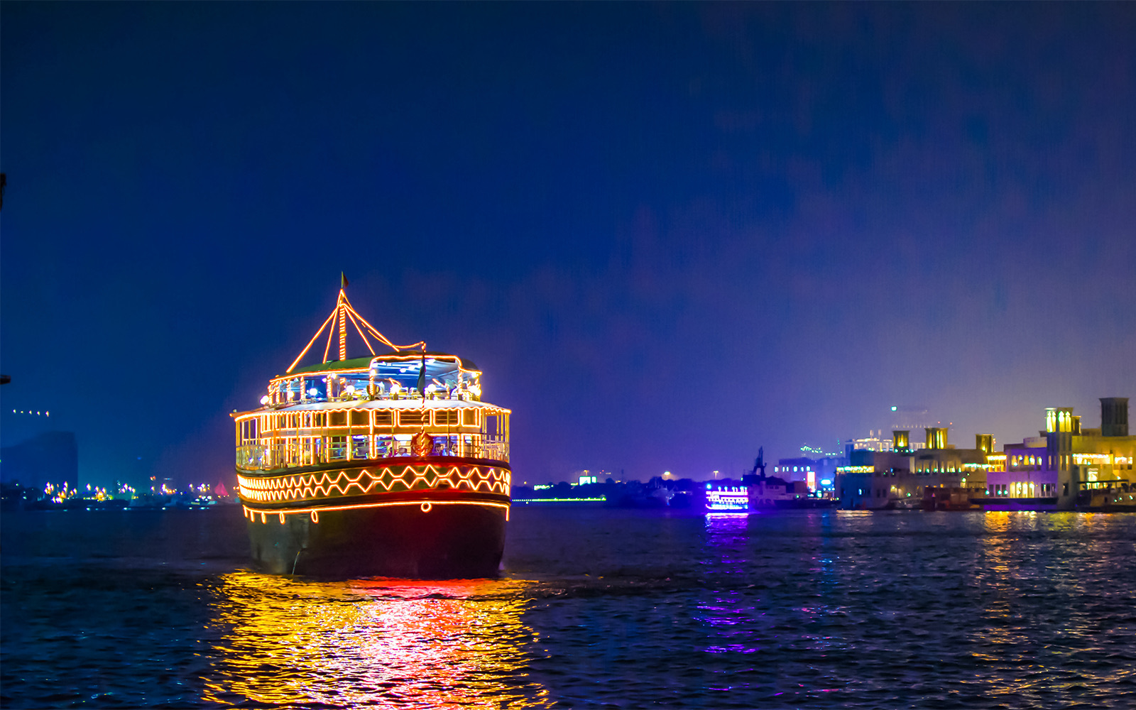 Dhow cruise with lights on Dubai Creek at night.