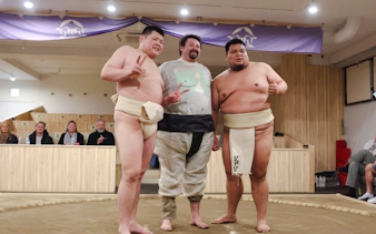 Tourist posing with sumo wrestlers at Shibuya Sumo Show in Tokyo.