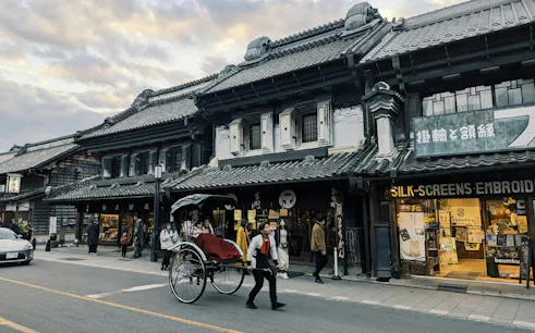 Rickshaw on a street in Kawagoe, Japan, with Edo-period buildings and shops in the background.