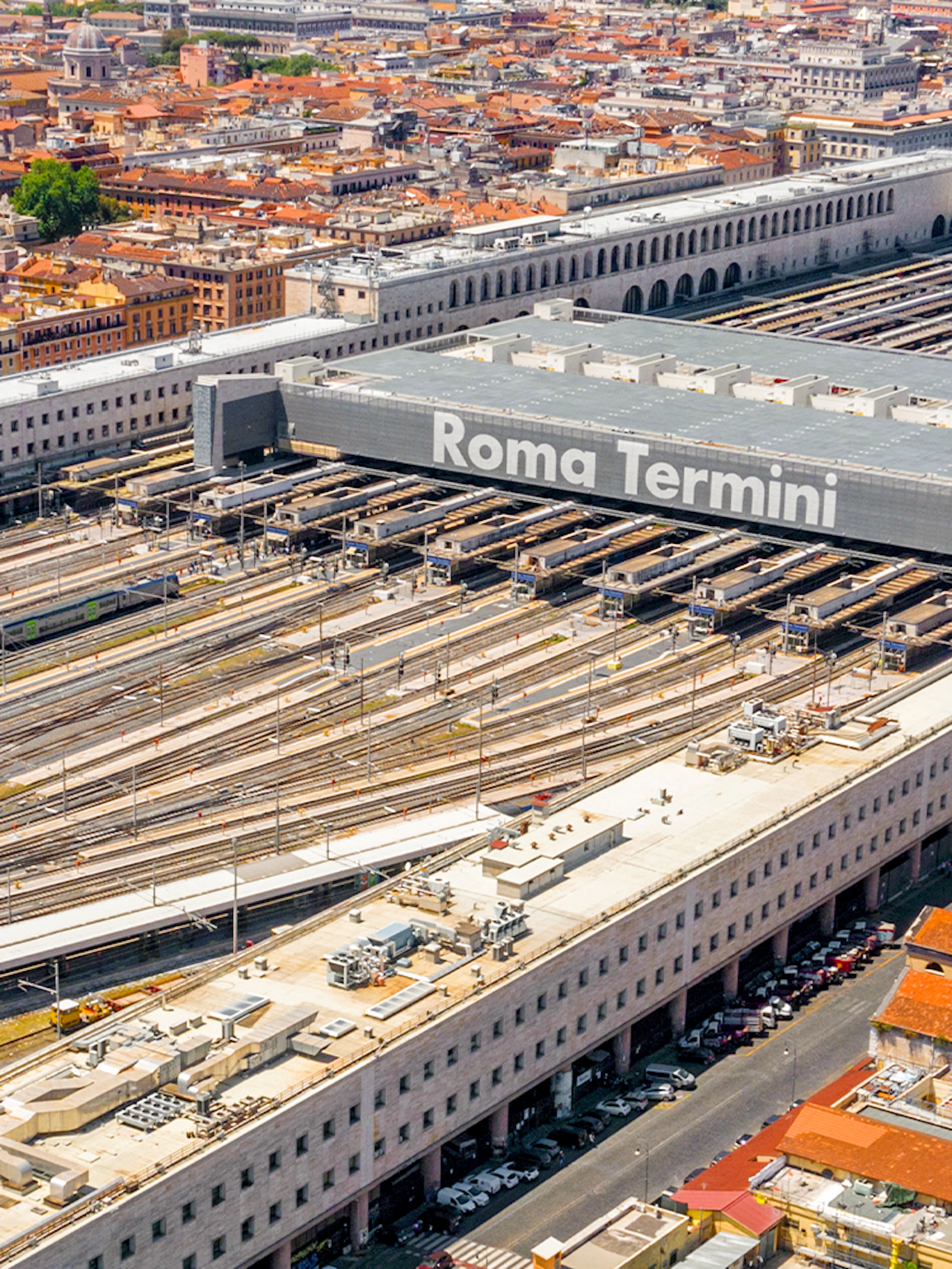 Aerial view of Roma Termini station with multiple train tracks and surrounding cityscape.