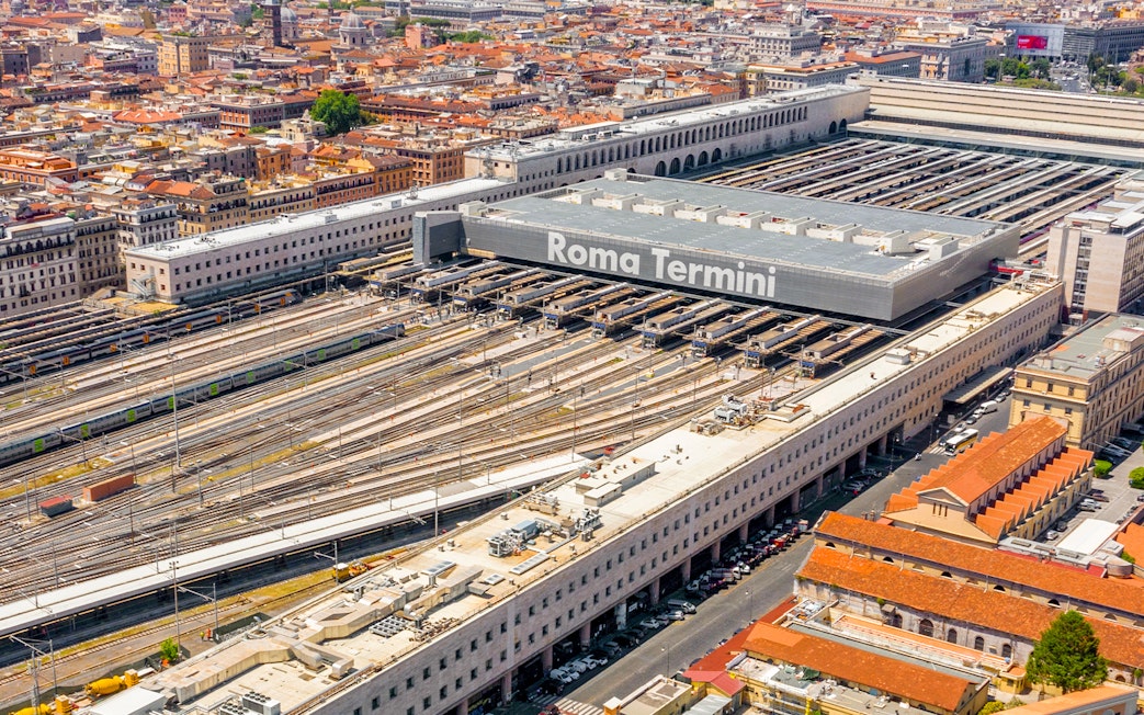 Aerial view of Roma Termini station with multiple train tracks and surrounding cityscape.