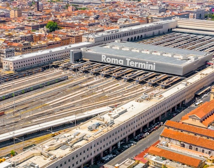 Aerial view of Roma Termini station with multiple train tracks and surrounding cityscape.
