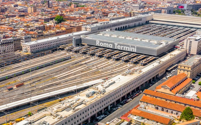 Aerial view of Roma Termini station with multiple train tracks and surrounding cityscape.