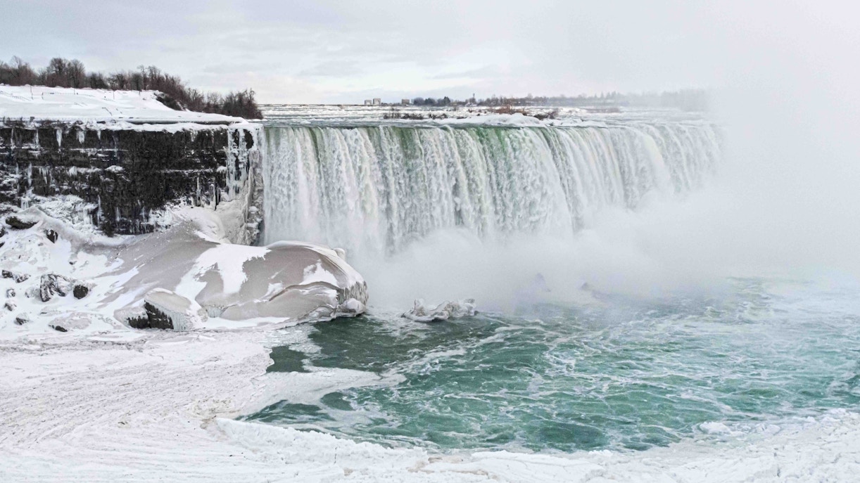 Niagara Falls covered in snow during winter, showcasing icy cascades and mist.