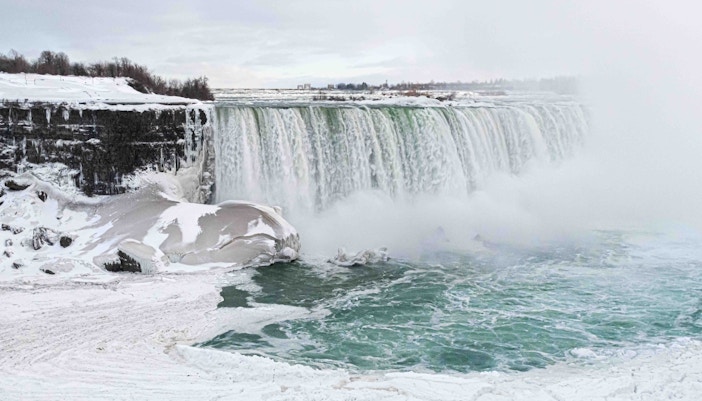 Niagara Falls covered in snow during winter, showcasing icy cascades and mist.