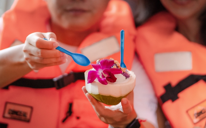 Tourists enjoying coconut ice cream at Damnoen Saduak Floating Market, Bangkok.