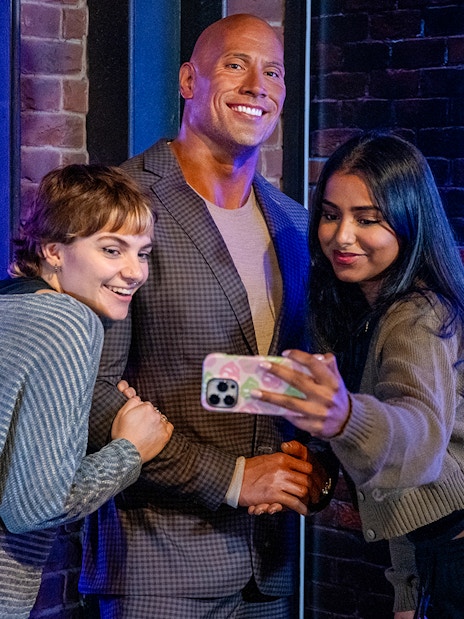 Visitors taking a selfie with a wax figure of a rock celebrity at Madame Tussauds London.