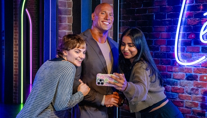Visitors taking a selfie with a wax figure of a rock celebrity at Madame Tussauds London.