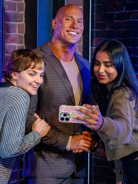 Visitors taking a selfie with a wax figure of a rock celebrity at Madame Tussauds London.