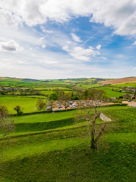Carisbrooke Castle grounds with lush green fields and distant village view.