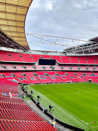 Wembley Stadium interior with red seats and green pitch in London.