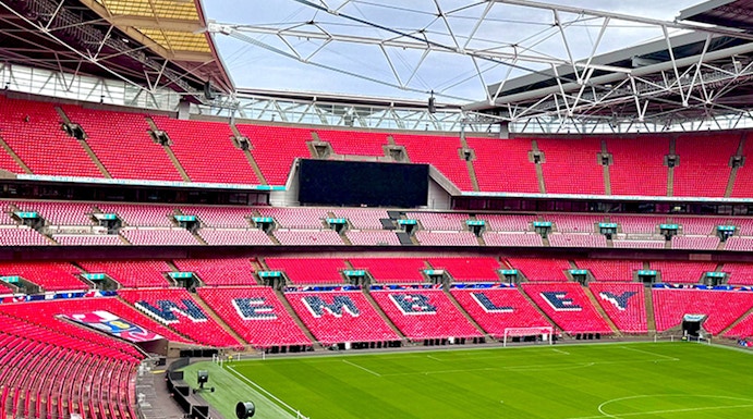 Wembley Stadium interior with red seats and green pitch in London.
