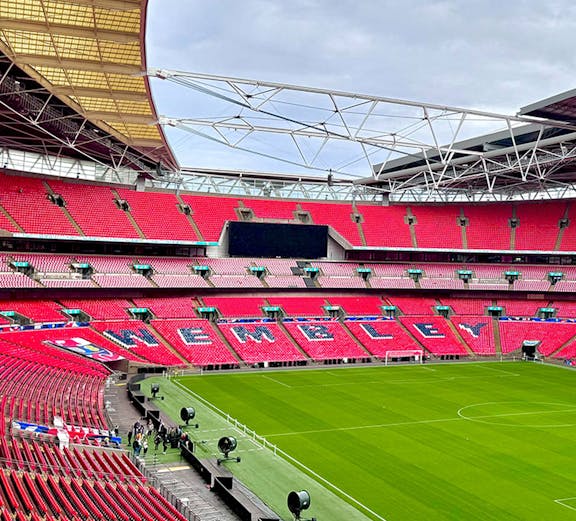 Wembley Stadium interior with red seats and green pitch in London.