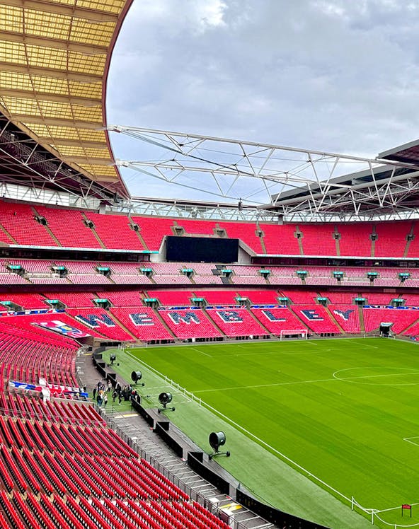 Wembley Stadium interior with red seats and green pitch in London.