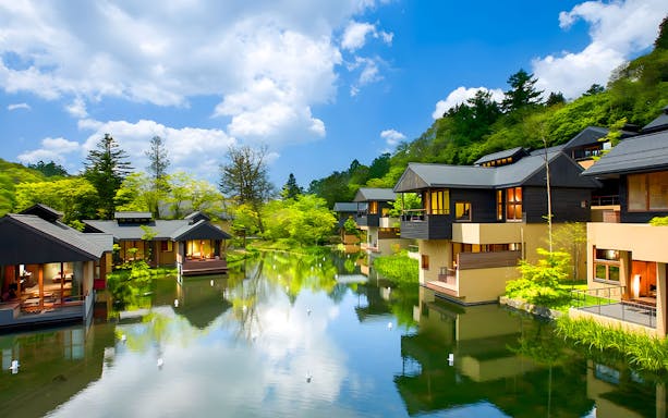 Karuizawa Hoshino Resorts area with modern lodges by a tranquil pond, surrounded by lush greenery.