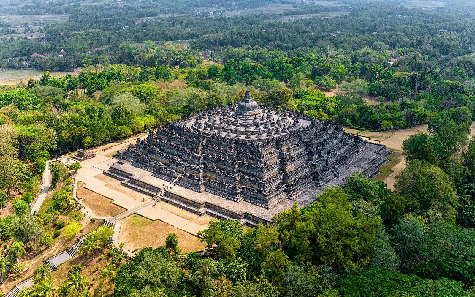 Aerial view of Borobudur Temple surrounded by lush greenery in Yogyakarta, Java, Indonesia.